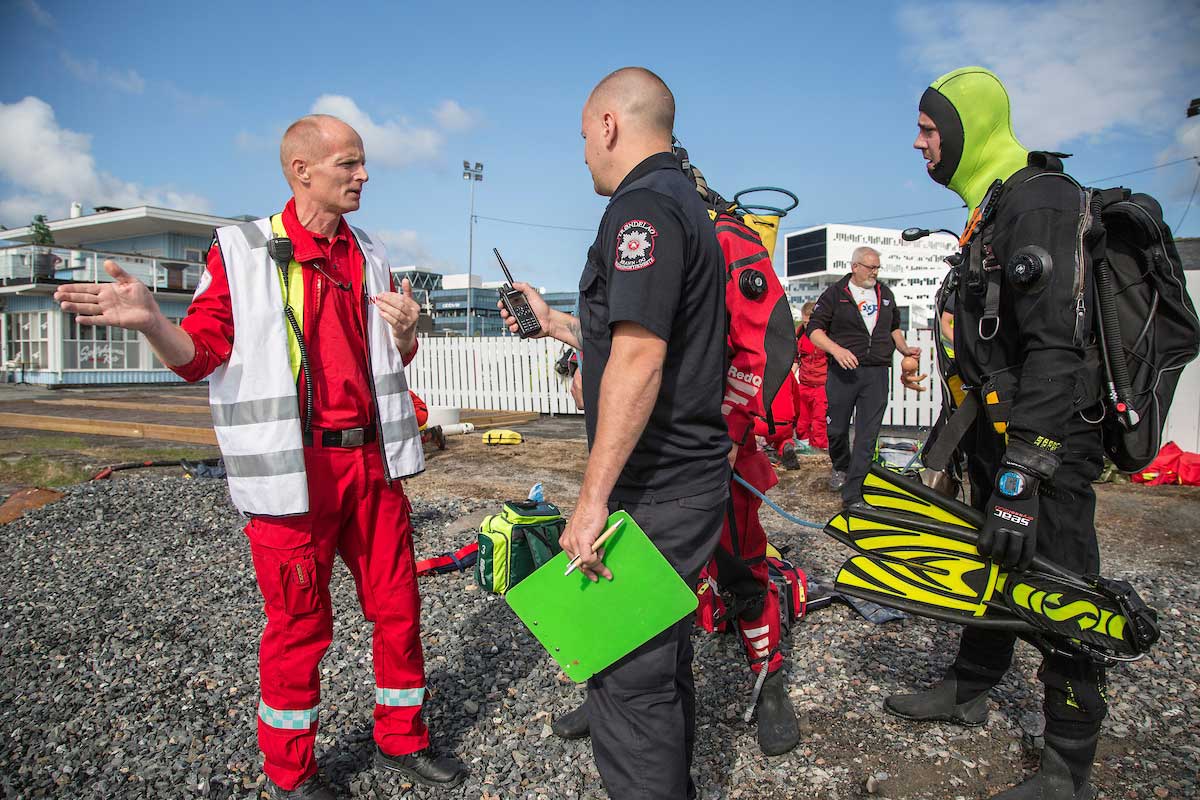 Mannskap fra legehelikopter, redningsdykkere i brann- og redningstjenesten og ambulansepersonell jobber sammen for å løse oppgaven.